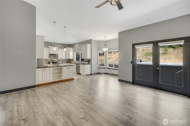unfurnished living room featuring french doors, light wood finished floors, ceiling fan, and baseboards