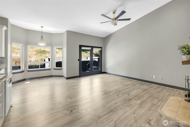 unfurnished living room with baseboards, ceiling fan, and light wood-type flooring