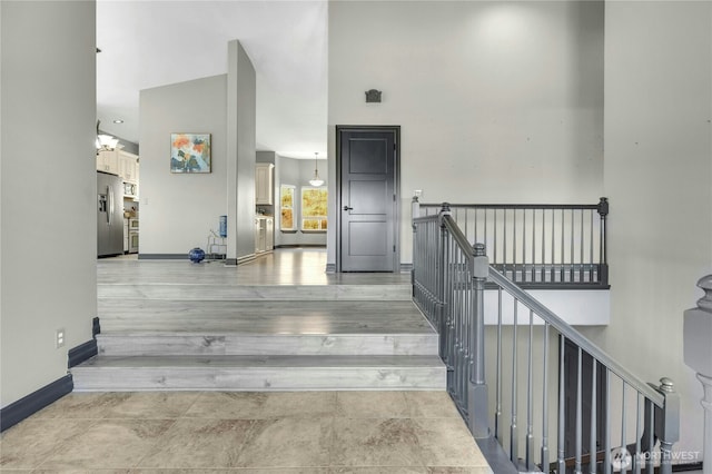 staircase featuring baseboards and a towering ceiling