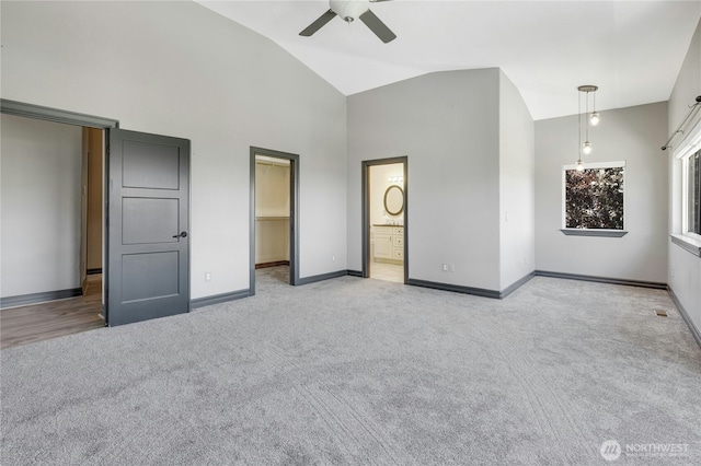 unfurnished bedroom with high vaulted ceiling, carpet, baseboards, ensuite bathroom, and a spacious closet