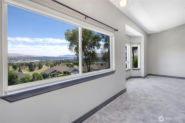 empty room with baseboards, vaulted ceiling, a mountain view, and carpet