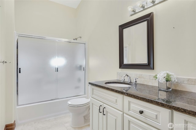 bathroom featuring vanity, tile patterned floors, toilet, and shower / bath combination with glass door