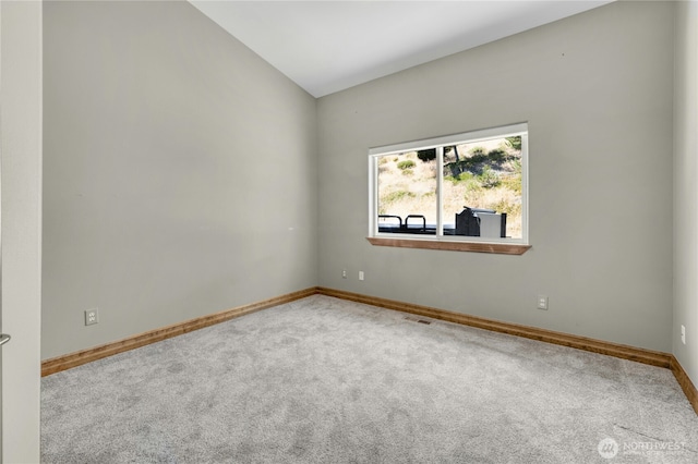carpeted spare room with baseboards, vaulted ceiling, and visible vents