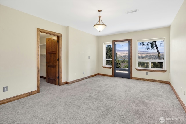 spare room featuring baseboards, light carpet, and visible vents