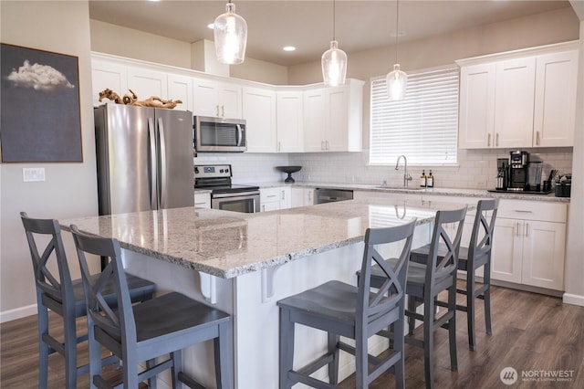 kitchen with white cabinets, stainless steel appliances, dark wood finished floors, and decorative backsplash