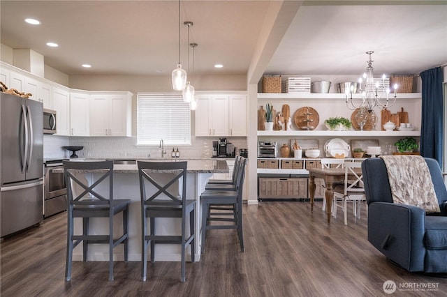 kitchen featuring white cabinets, a breakfast bar, stainless steel appliances, and dark wood finished floors