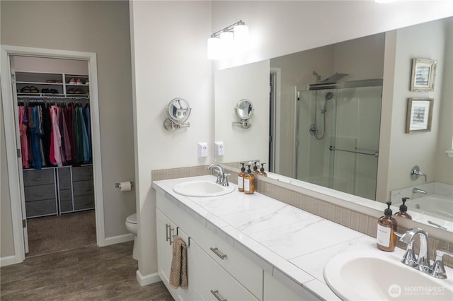 bathroom featuring wood finished floors, a sink, a stall shower, and double vanity