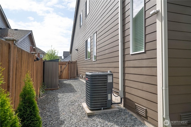 view of property exterior with fence, central AC unit, and a gate