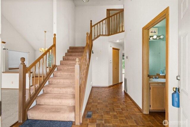 stairway with visible vents, baseboards, and high vaulted ceiling