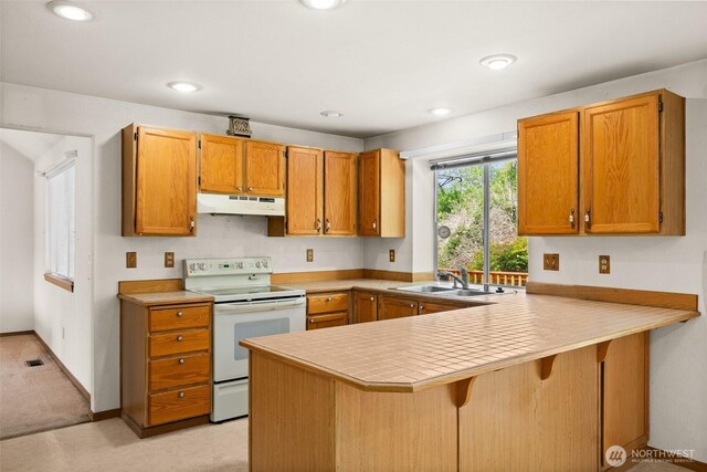 kitchen featuring white range with electric stovetop, a sink, light countertops, a peninsula, and under cabinet range hood