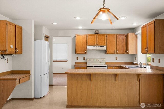 kitchen with a sink, white appliances, brown cabinetry, a peninsula, and under cabinet range hood