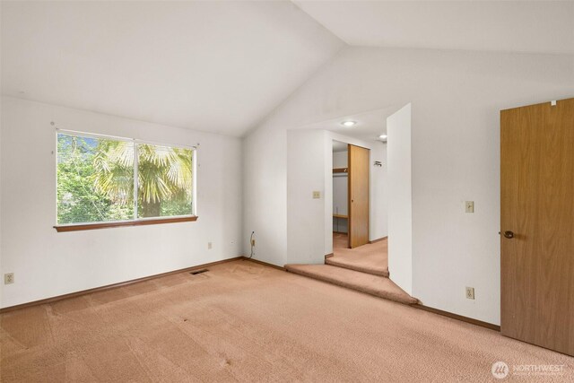 unfurnished room with carpet flooring, baseboards, visible vents, and lofted ceiling