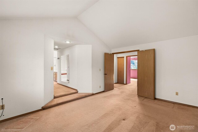 unfurnished room featuring light colored carpet and lofted ceiling
