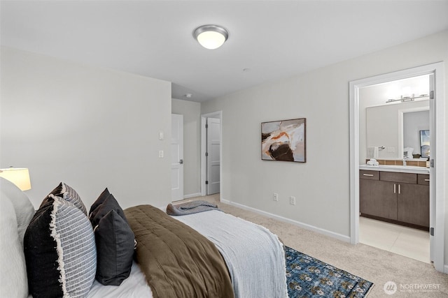 bedroom with baseboards, a sink, ensuite bathroom, and light carpet