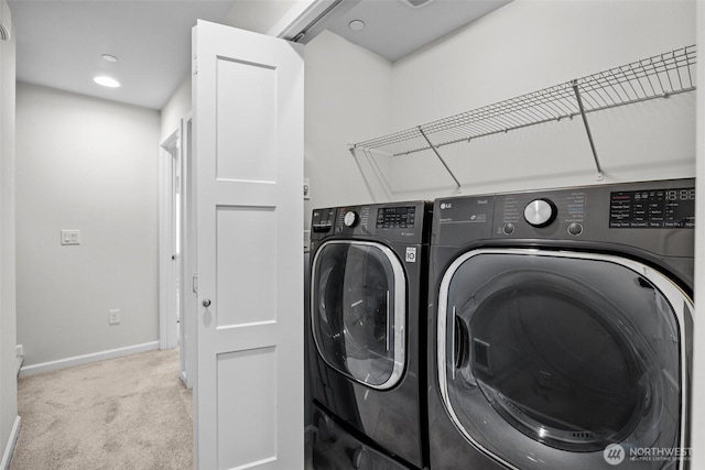 clothes washing area featuring carpet flooring, laundry area, baseboards, and washing machine and clothes dryer