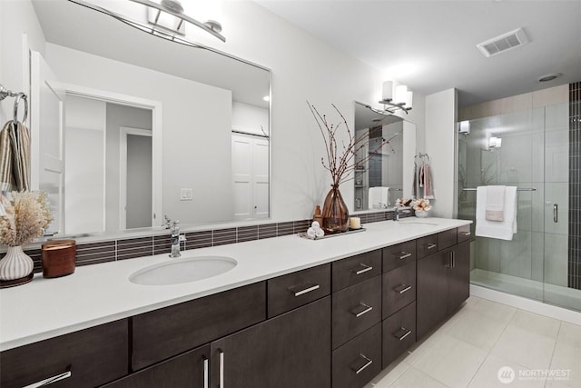 bathroom featuring a sink, tile patterned floors, a stall shower, and double vanity