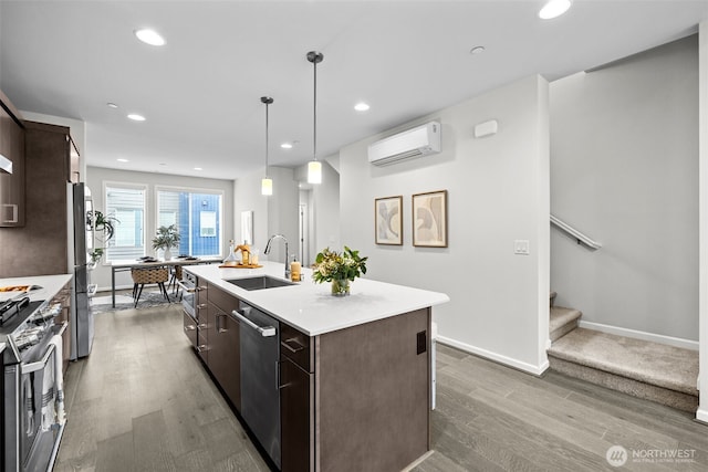 kitchen with dark brown cabinets, a sink, a wall mounted air conditioner, stainless steel appliances, and wood finished floors