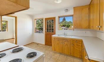 kitchen with plenty of natural light, light countertops, stove, and brown cabinetry