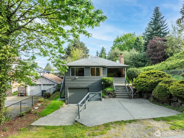 back of house with fence, a chimney, driveway, and stairway