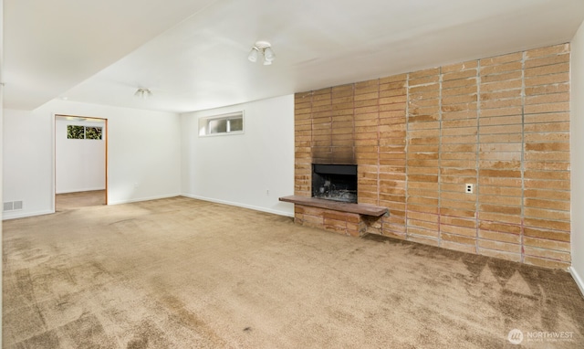 unfurnished living room featuring baseboards, carpet flooring, a brick fireplace, and visible vents