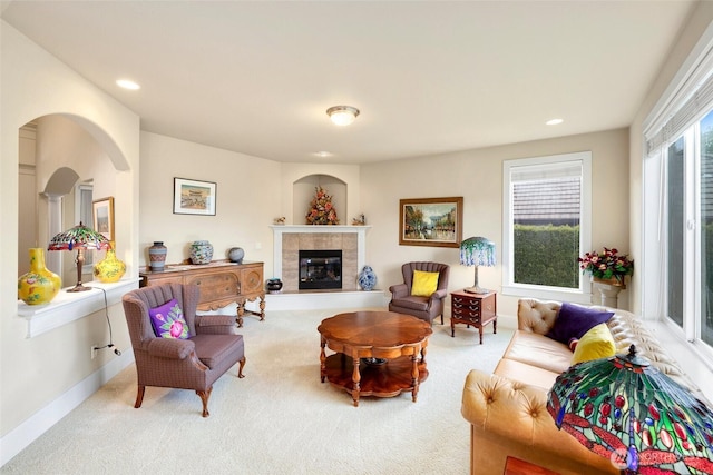 carpeted living area with recessed lighting, baseboards, a tiled fireplace, and arched walkways
