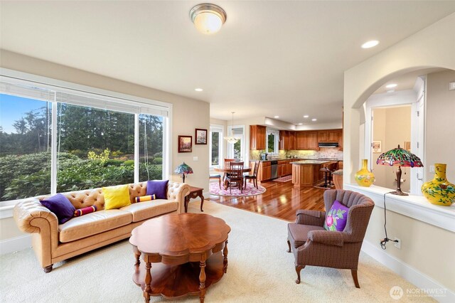 carpeted living room with arched walkways, baseboards, and recessed lighting