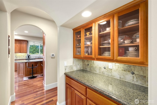 bar with recessed lighting, arched walkways, backsplash, and wood finished floors