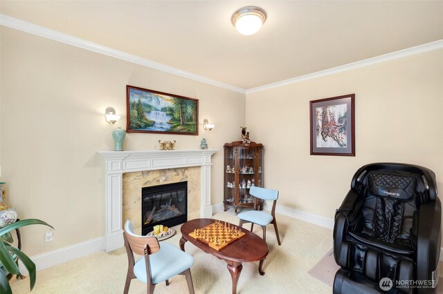 carpeted living area featuring baseboards, ornamental molding, and a high end fireplace