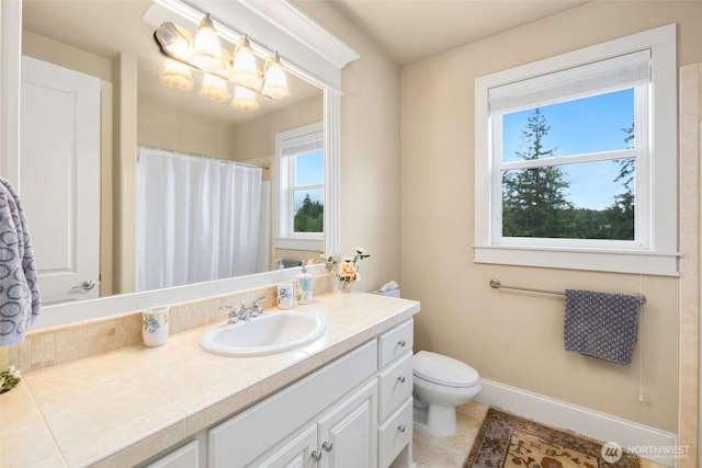 bathroom with vanity, curtained shower, toilet, baseboards, and a chandelier