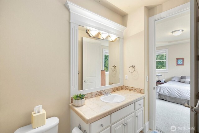 ensuite bathroom with backsplash, toilet, ensuite bathroom, and vanity