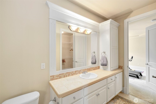 bathroom with vanity, toilet, and tasteful backsplash