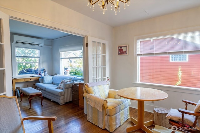 living area with a wall mounted AC, wood finished floors, and a notable chandelier