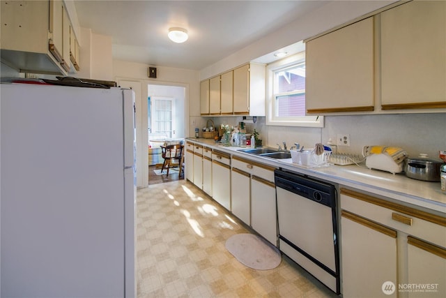 kitchen with a sink, light countertops, light floors, white appliances, and cream cabinetry