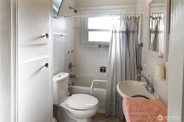 full bathroom with a sink, tile walls, toilet, and shower / bath combination with curtain