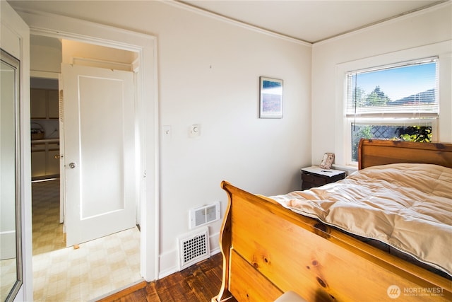 bedroom featuring visible vents, baseboards, crown molding, and wood finished floors