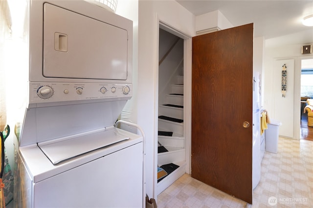 laundry room with laundry area, light floors, and stacked washer / dryer