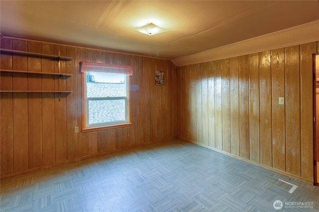 spare room featuring baseboards and wood walls