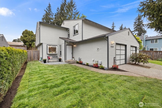 back of property with fence, a lawn, and a garage