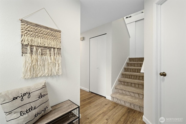staircase featuring baseboards and wood finished floors