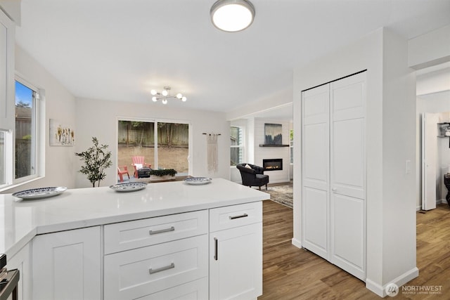 kitchen featuring light wood-style floors, light countertops, white cabinets, and a large fireplace