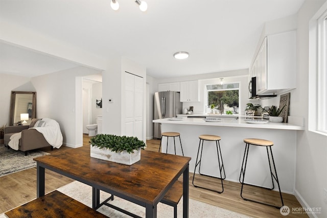 dining space featuring light wood-style floors and baseboards
