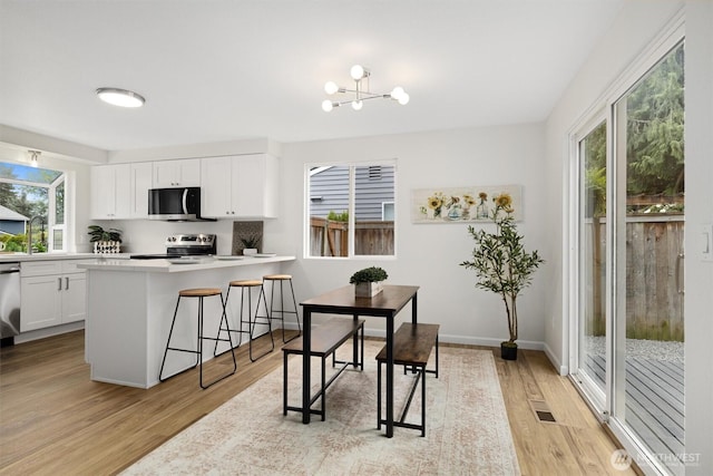 dining area featuring an inviting chandelier, light wood finished floors, baseboards, and visible vents