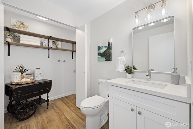 bathroom featuring vanity, baseboards, toilet, and wood finished floors