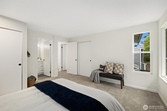 bedroom featuring baseboards, ensuite bathroom, and light carpet