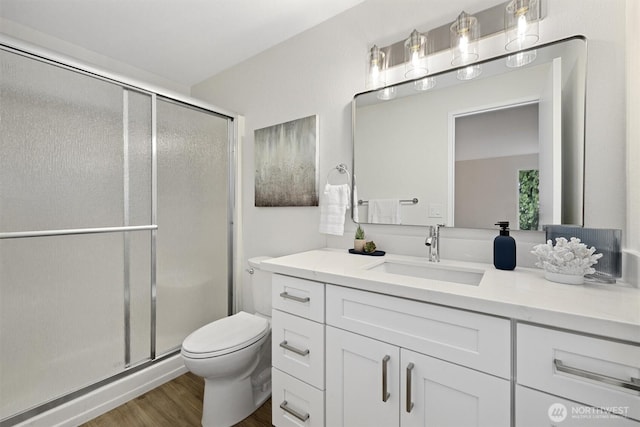 bathroom featuring vanity, a shower stall, toilet, and wood finished floors