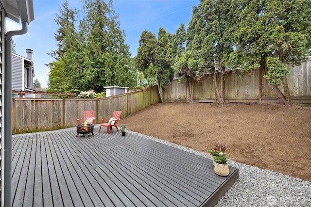 wooden deck featuring a fenced backyard and a fire pit