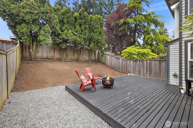 deck featuring a fenced backyard and a fire pit
