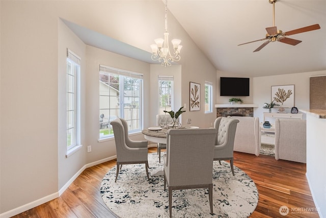 dining area with light wood-style flooring, lofted ceiling, a healthy amount of sunlight, and a fireplace