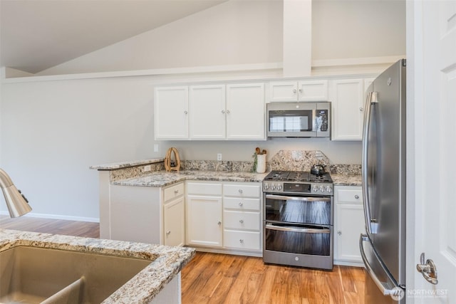 kitchen featuring a peninsula, white cabinetry, a sink, appliances with stainless steel finishes, and vaulted ceiling
