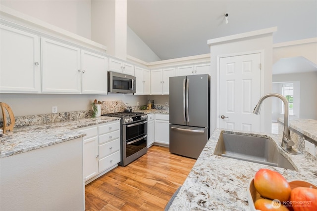 kitchen featuring a sink, light wood finished floors, white cabinets, and stainless steel appliances